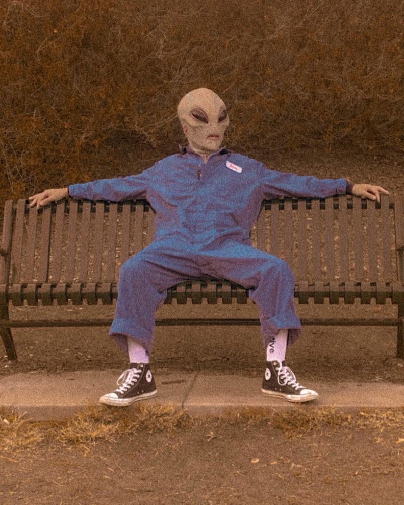 Alien Area 51 mask spotted on park bench in vintage jumpsuit and sneakers — The Terror Lab.