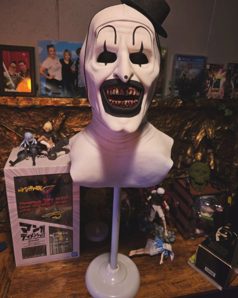 Close-up of the Art the Clown mask displayed on a stand, surrounded by collectibles and horror memorabilia — The Terror Lab.