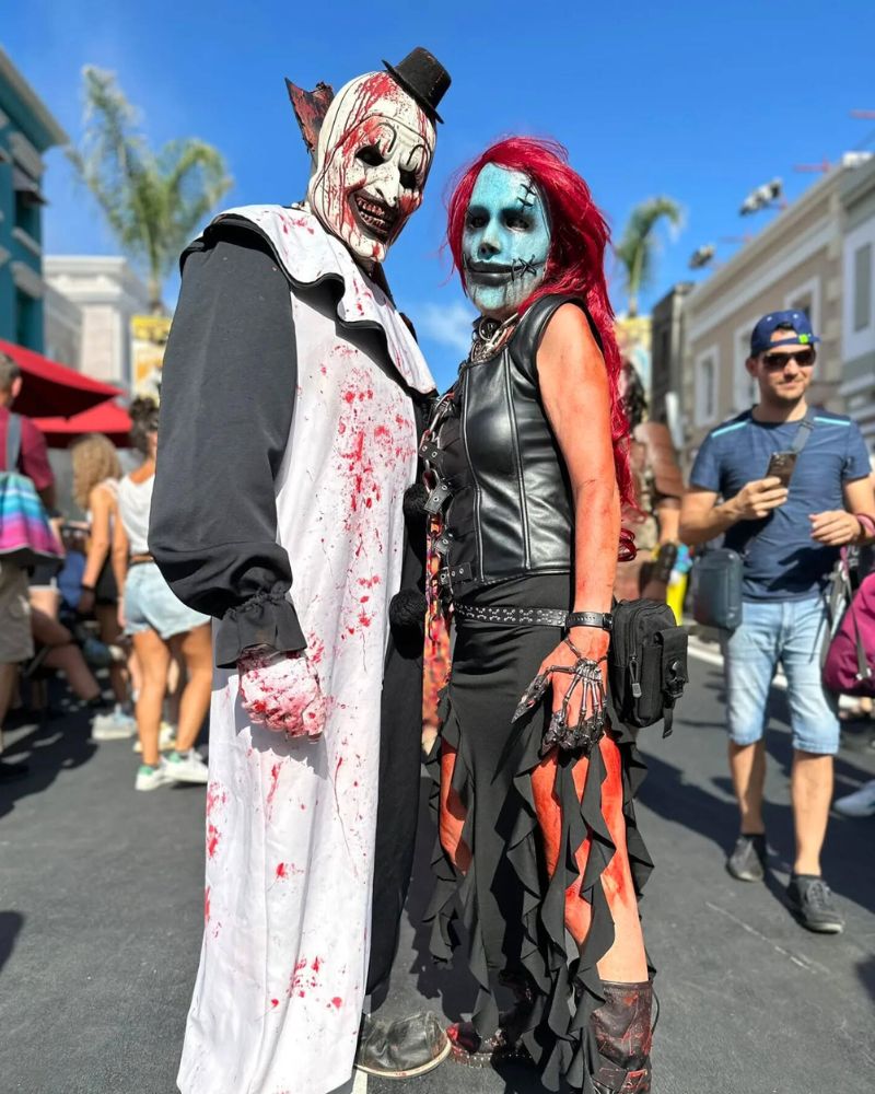 Art the Clown and a horror-themed companion posing in full costume under the sun at a Halloween street festival — The Terror Lab.