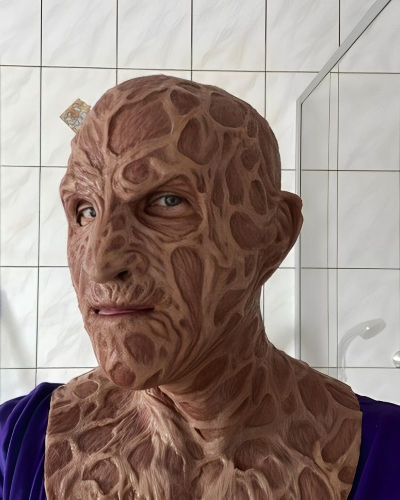 A customer wearing a realistic Freddy Krueger mask with full neck detailing, posing in a bathroom setting – The Terror Lab