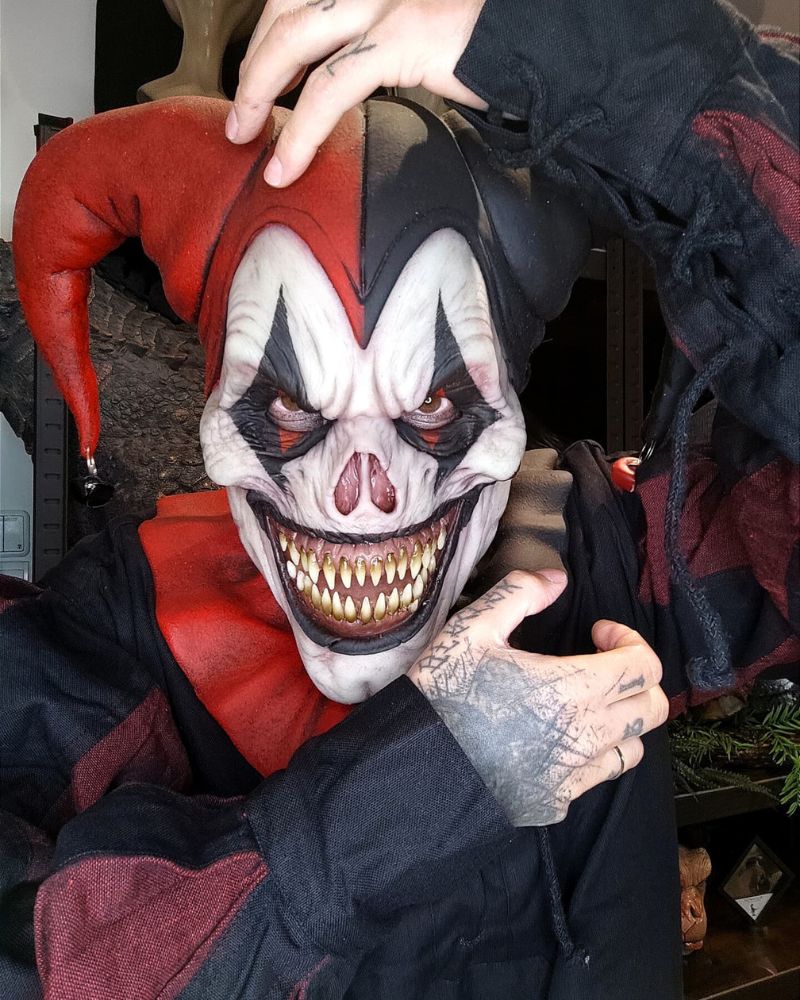 Terrifying red and black harlequin jester mask close-up showing intricate texture and sinister grin — The Terror Lab.