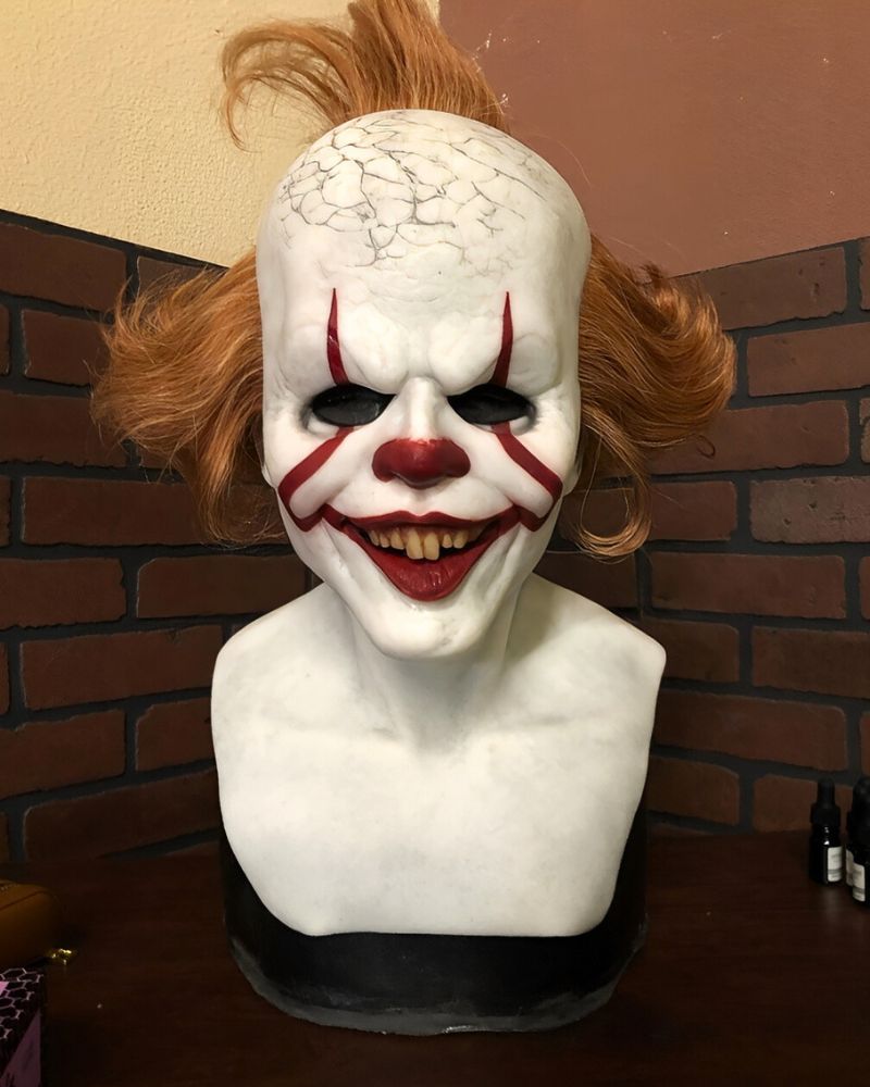 Pennywise clown mask with cracked skull detail and sinister smile, captured in close-up bust display — The Terror Lab