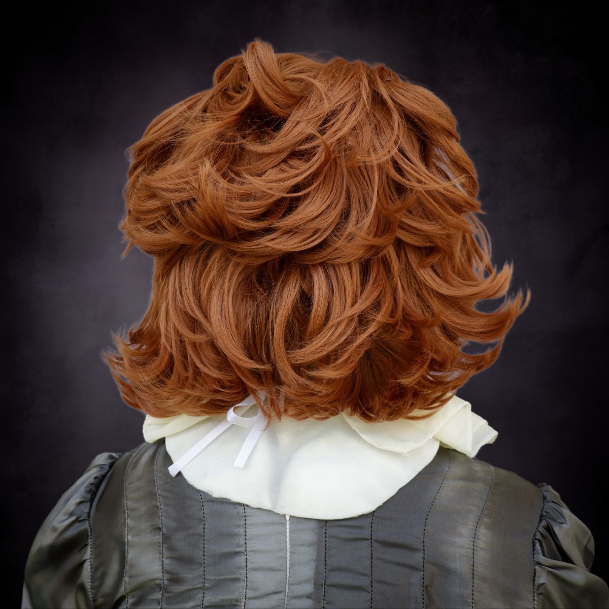 Wig with brown hair of Pennywise mask styled in an old-fashioned manner on a dark background