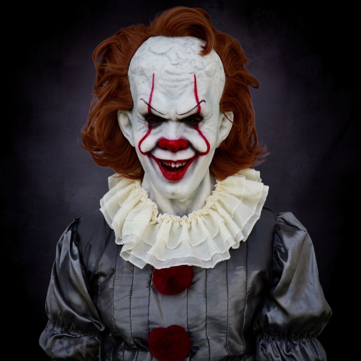 Pennywise Clown with white face, red clown open mouth, and a dark background