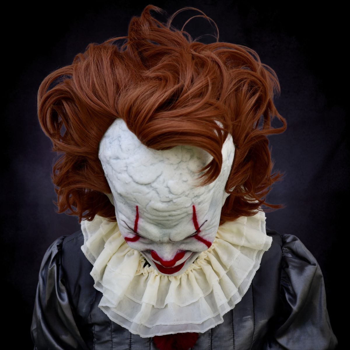 Person wearing Pennywise clown mask from The Terror Lab with red hair and a dark background