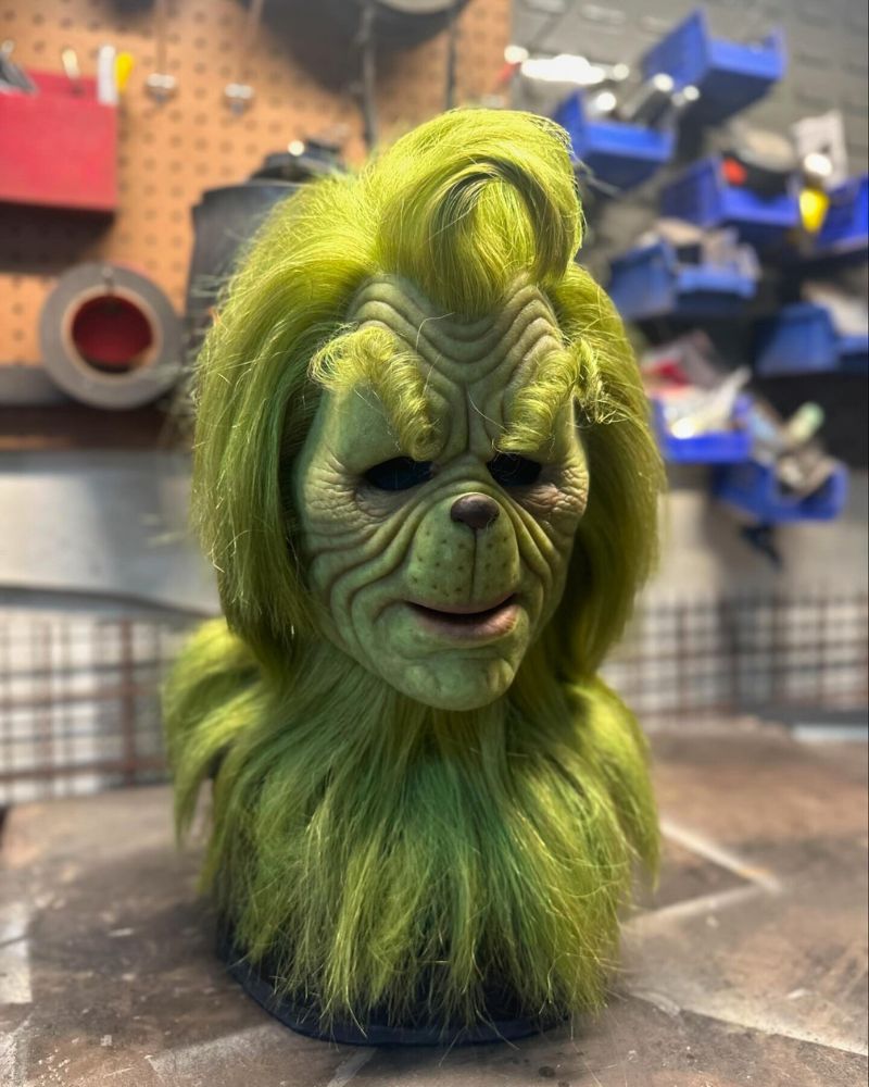 Close-up of the Stealer of Christmas realistic mask displayed in a workshop, showing detailed green fur and sculpted features — ideal for Halloween and Christmas events from The Terror Lab