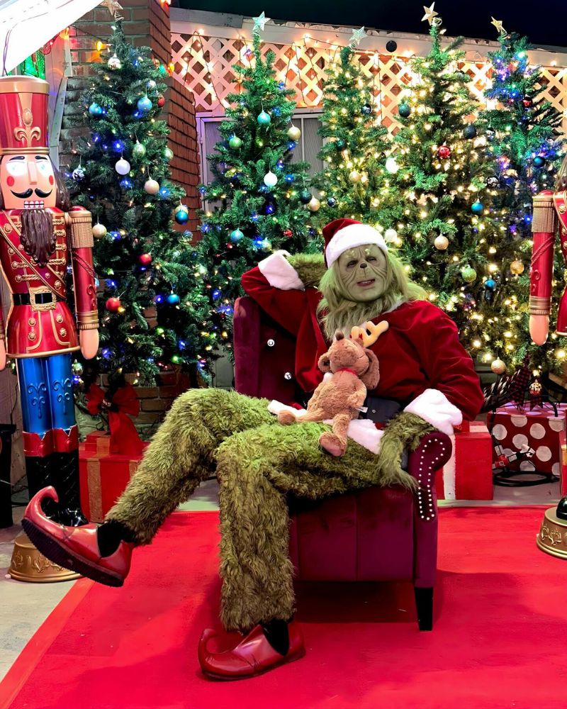 The Stealer of Christmas full costume spotted at a holiday event, sitting in a red velvet chair with decorated Christmas trees in the background — from The Terror Lab.
