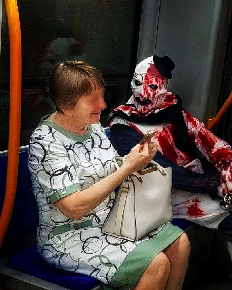 Wearing the Art the Clown mask and full costume, casually riding public transport with a cheerful passenger during a Halloween night — The Terror Lab.