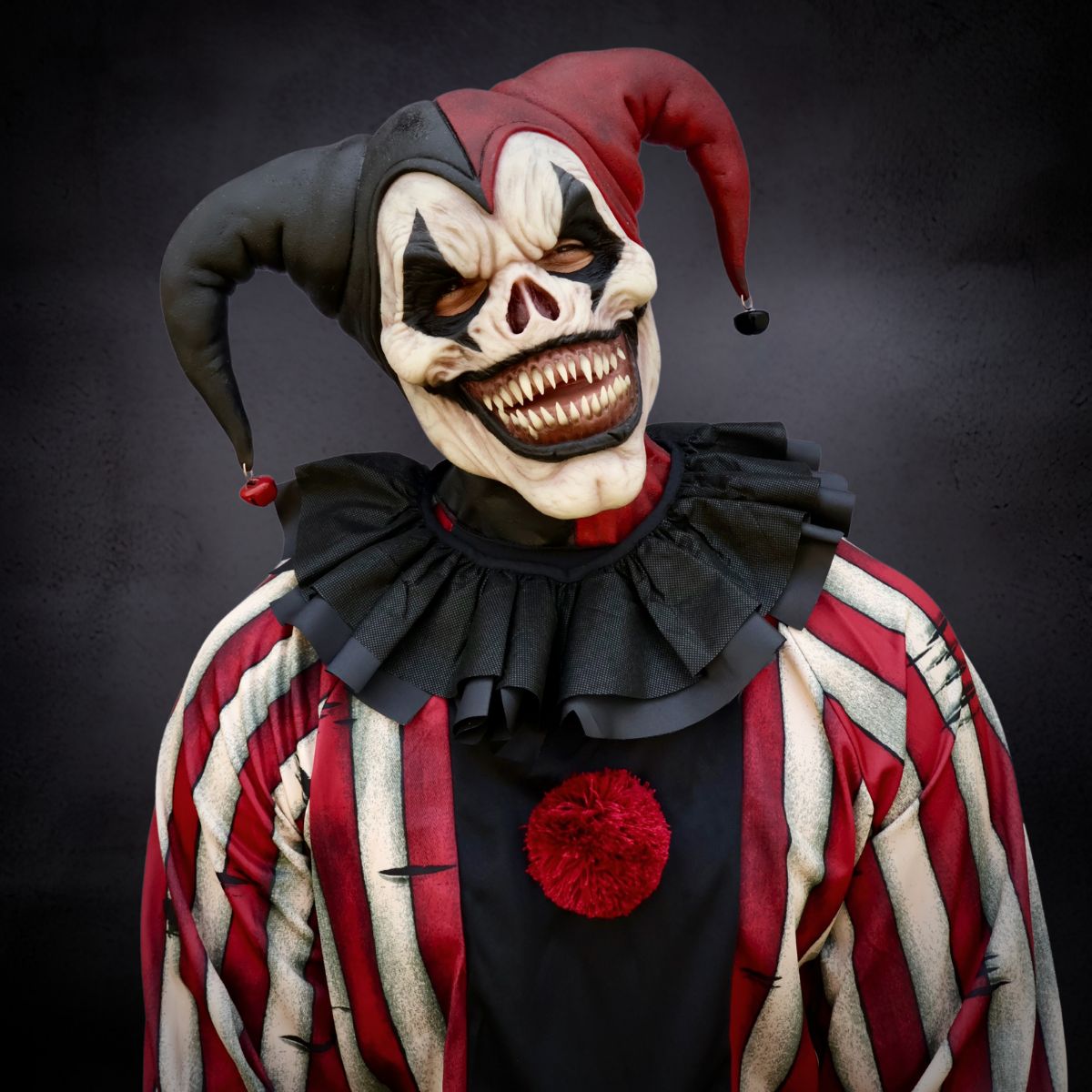 Horror-themed jester the clown costume with red and black hat and outfit on a dark background