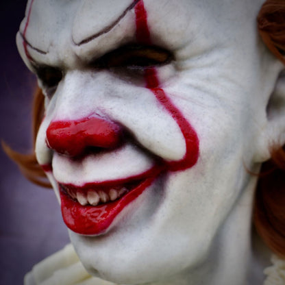 Close-up of Pennywise realistic clown with white face, red lips, and red markings on a dark background