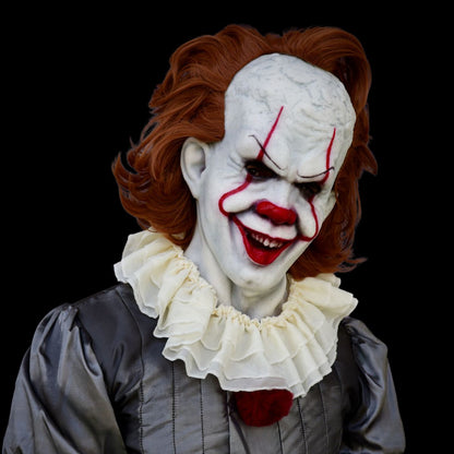 Person wearing a clown mask with red hair and white face makeup on a black background
