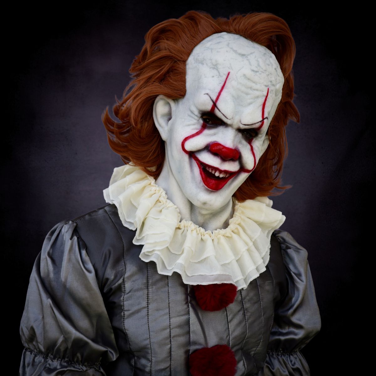 Pennywise horror Clown with white face, red hair, and red nose against a dark background from The Terror Lab