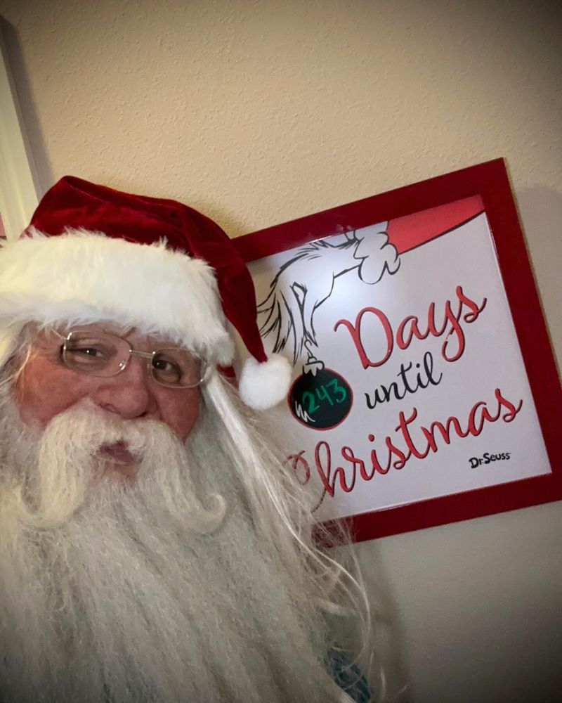 Realistic Santa Claus mask and costume worn by a customer during the holiday season, smiling in front of a Christmas countdown sign — The Terror Lab.